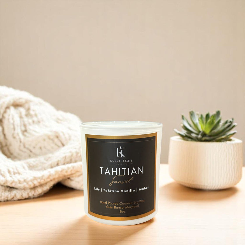 Knight Light Candles Tahitian Sunset candle on a wooden surface next to a succulent and a cozy knit blanket, showcasing a clean, minimalist home decor setting.